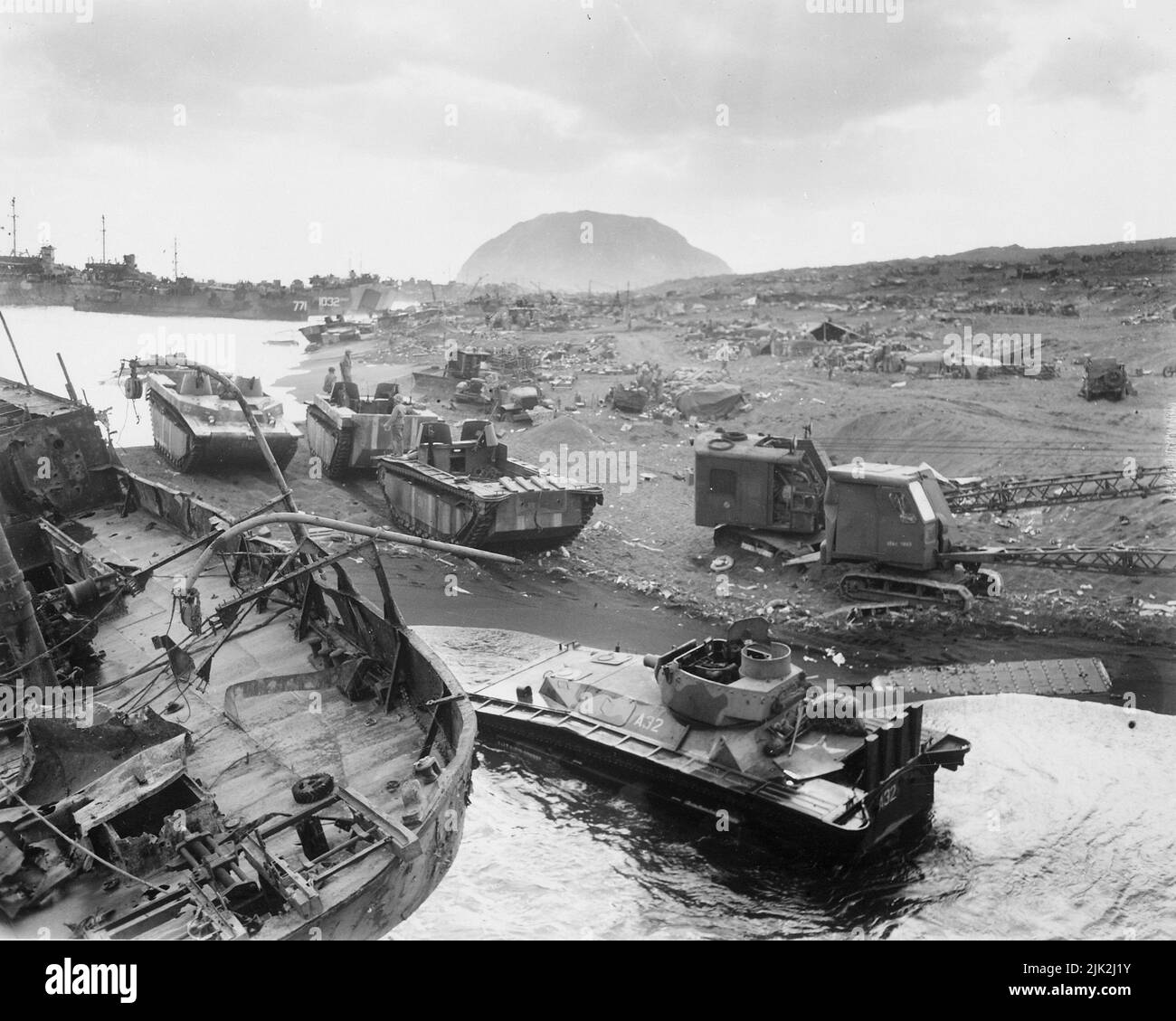 The detritus of war scattered on the beach of Iwo Jima after the US landings there. The focus of the fighting, the peak of Suribachi can be seen in the background Stock Photo