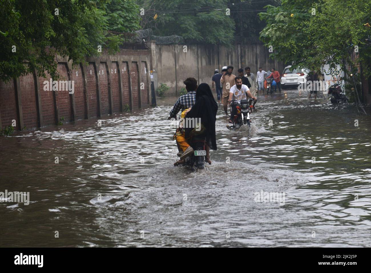 Lahore, Pakistan. 29th July, 2022. Pakistani people wade through a