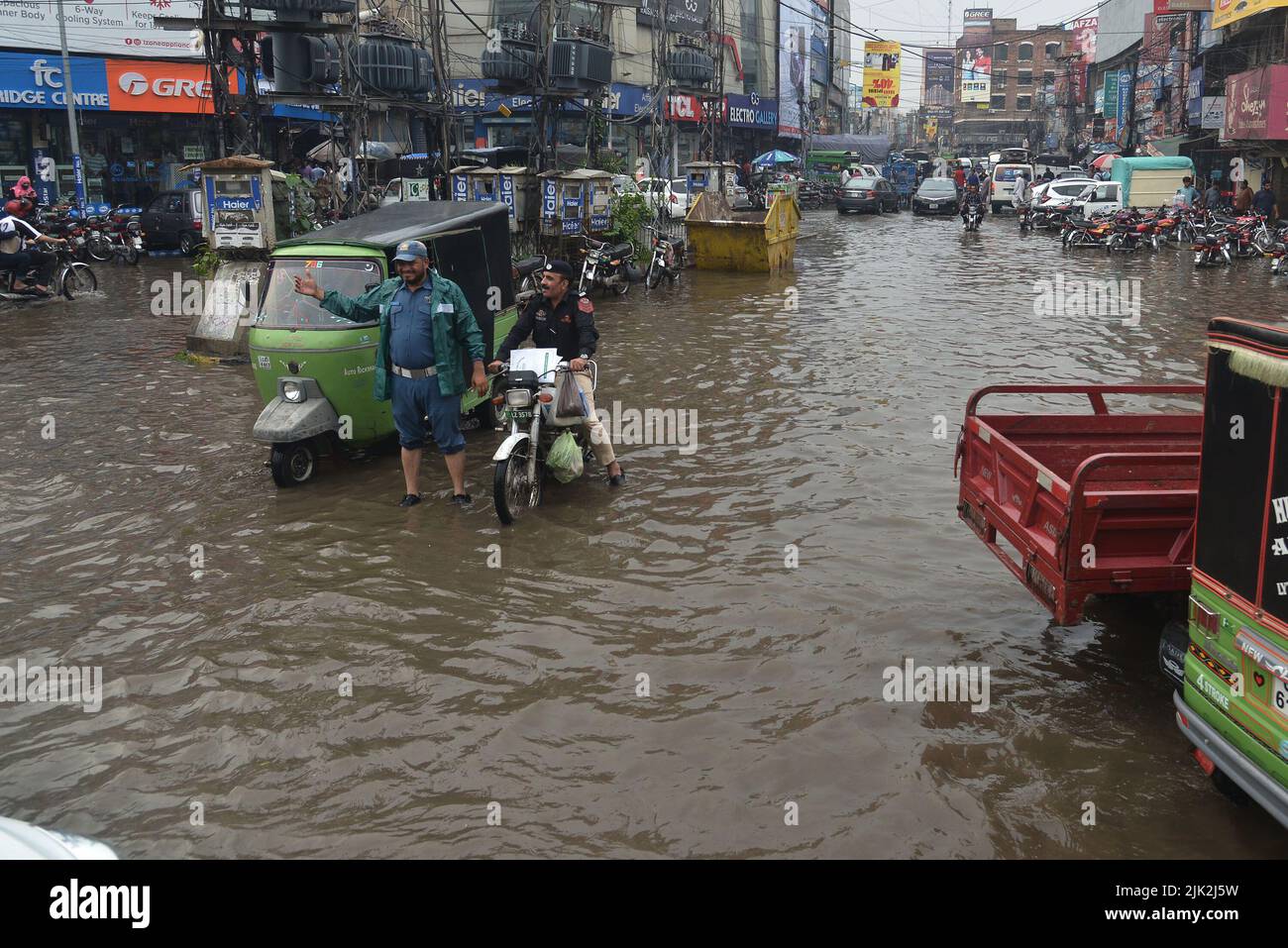 Lahore, Pakistan. 29th July, 2022. Pakistani people wade through a