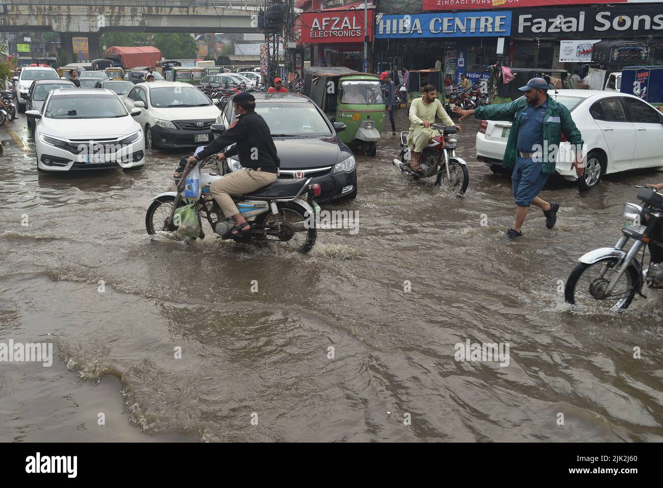 Lahore, Pakistan. 29th July, 2022. Pakistani people wade through a