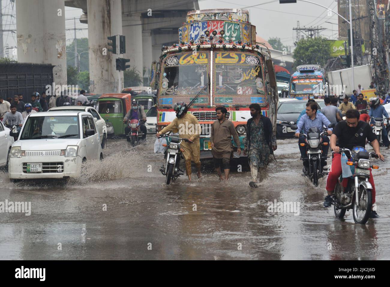 Lahore, Pakistan. 29th July, 2022. Pakistani people wade through a