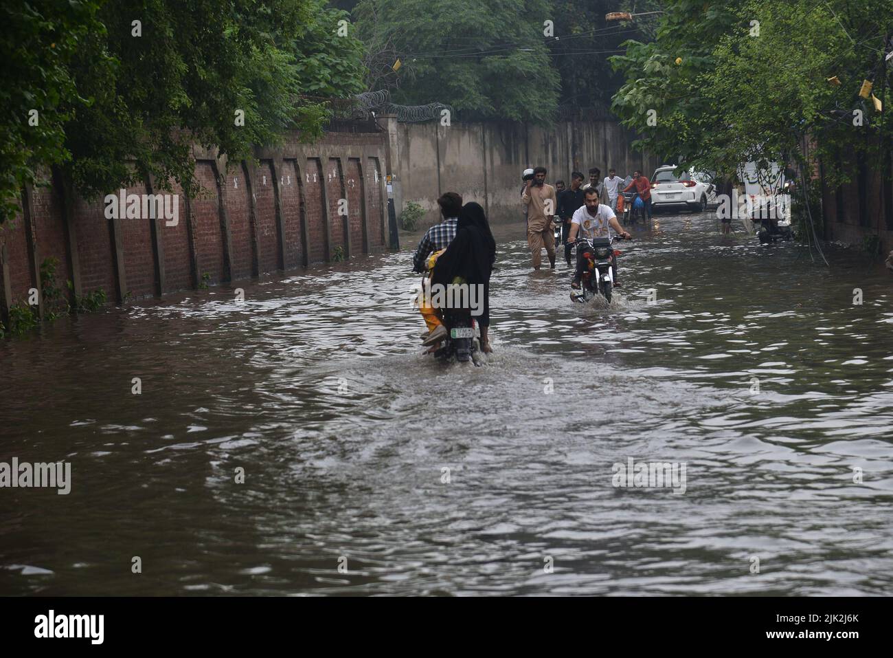 Lahore, Pakistan. 29th July, 2022. Pakistani people wade through a