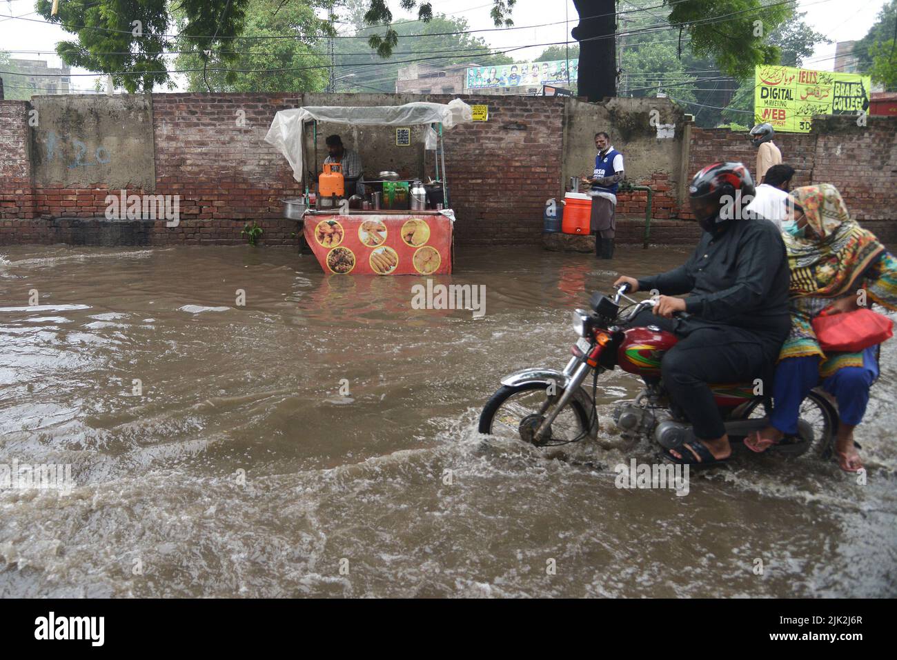 Lahore, Pakistan. 29th July, 2022. Pakistani people wade through a