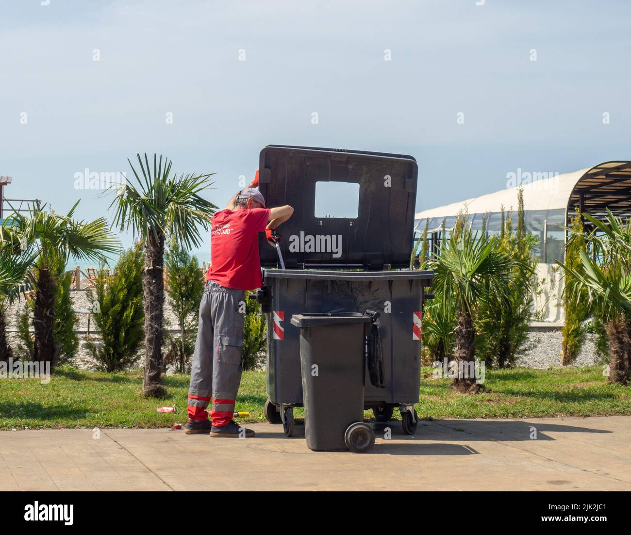 The garbage man puts the garbage in a large garbage container. Man at
