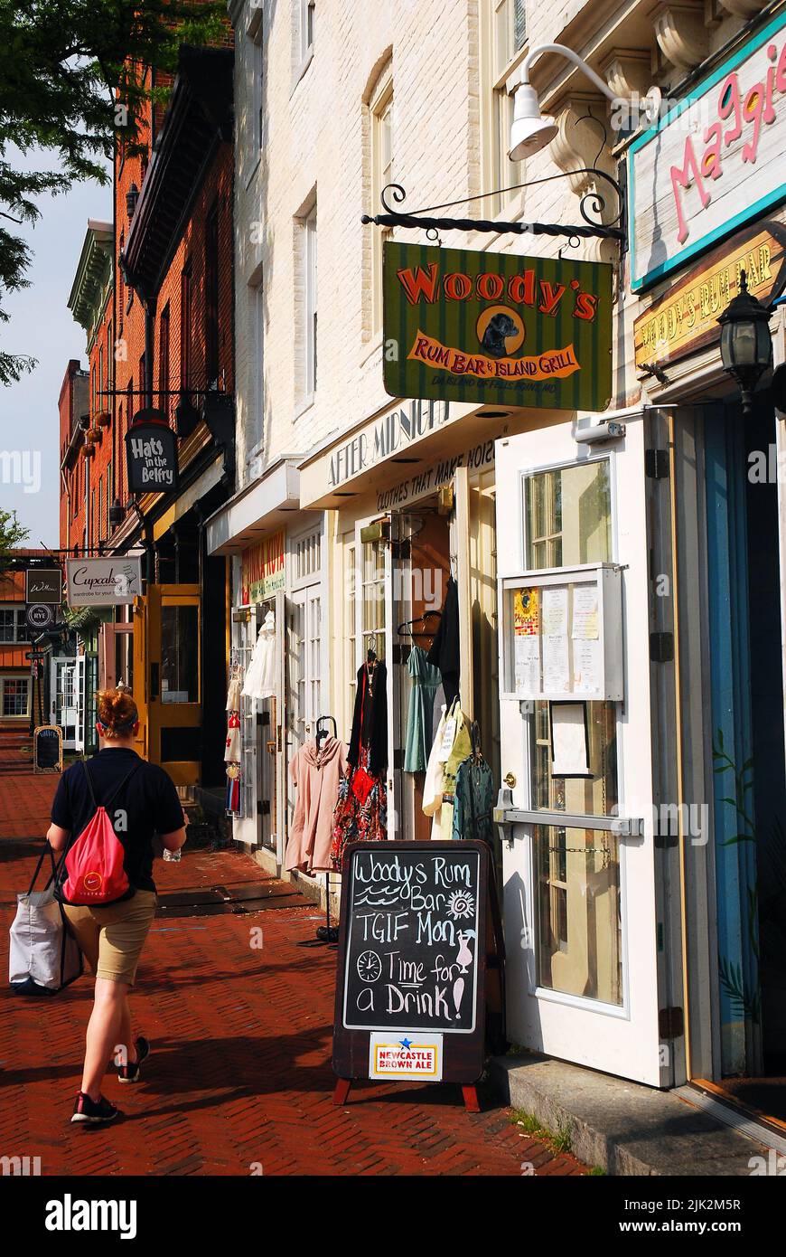 A young woman walks by a taverns and boutique stores and Small businesses in the Fells Point neighborhood of  Maryland Stock Photo