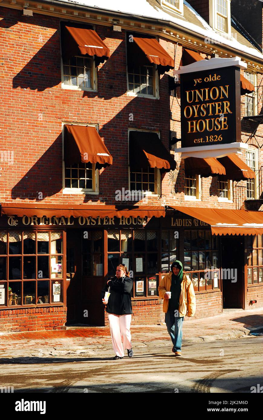 Two people cross the street on a cold winter’s day in front of the historic Oyster House in Boston Stock Photo