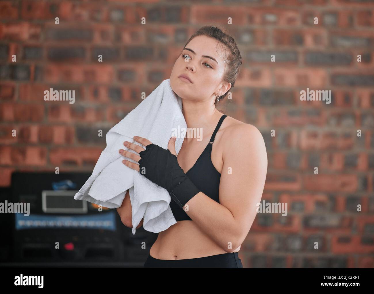 Healthy, fit and active female boxer wiping sweat with a towel after a workout in the gym or health club. Young woman completing and finishing Stock Photo