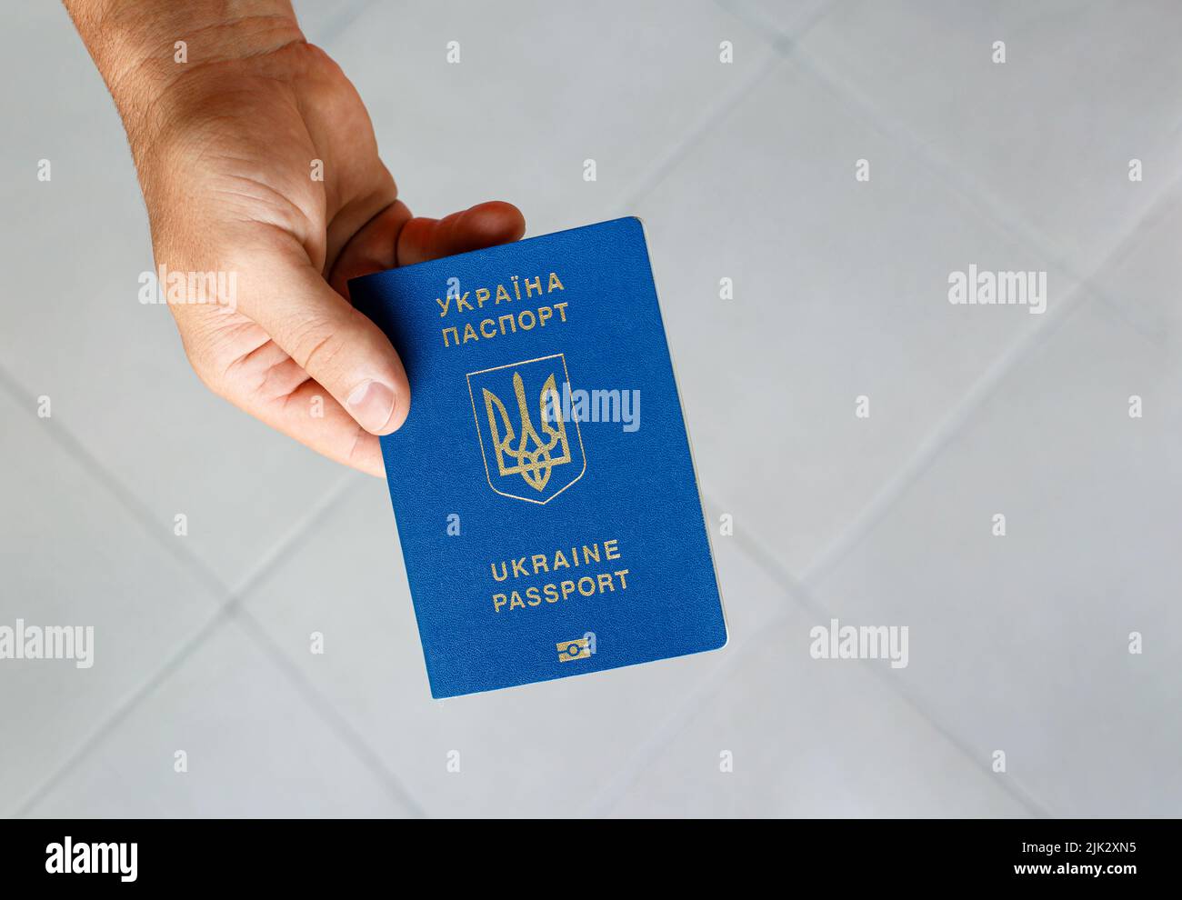 Passport of a citizen of Ukraine in a male hand on a gray background, close-up. Stock Photo