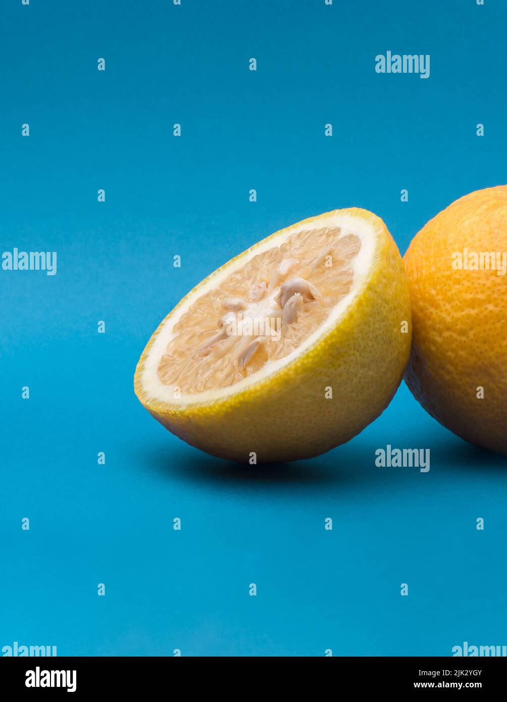 sweet orange fruit slices, isolated on blue background, complementary color theme Stock Photo