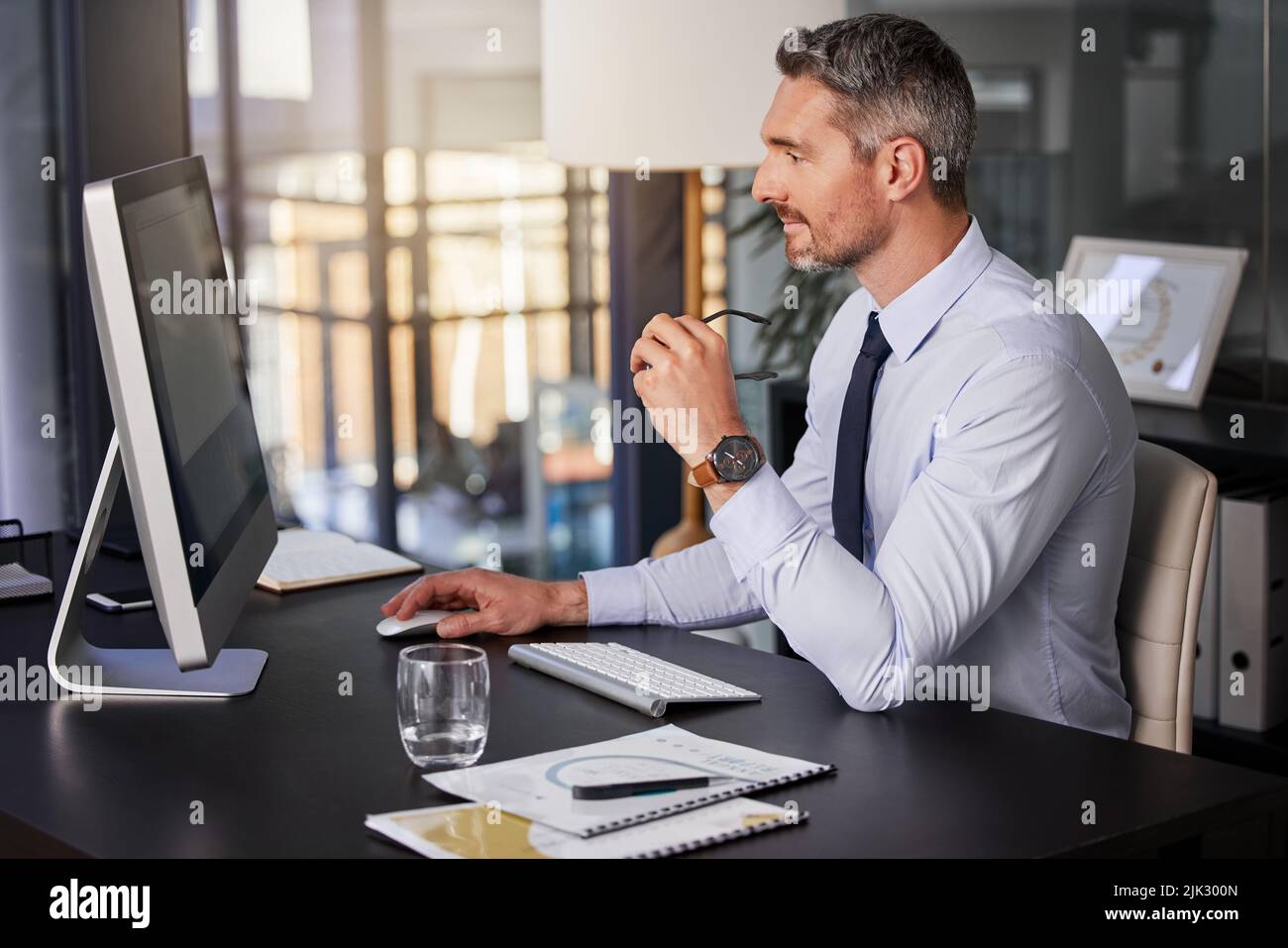 I give my best on everything I work on. a businessman using his computer while sitting at his desk. Stock Photo