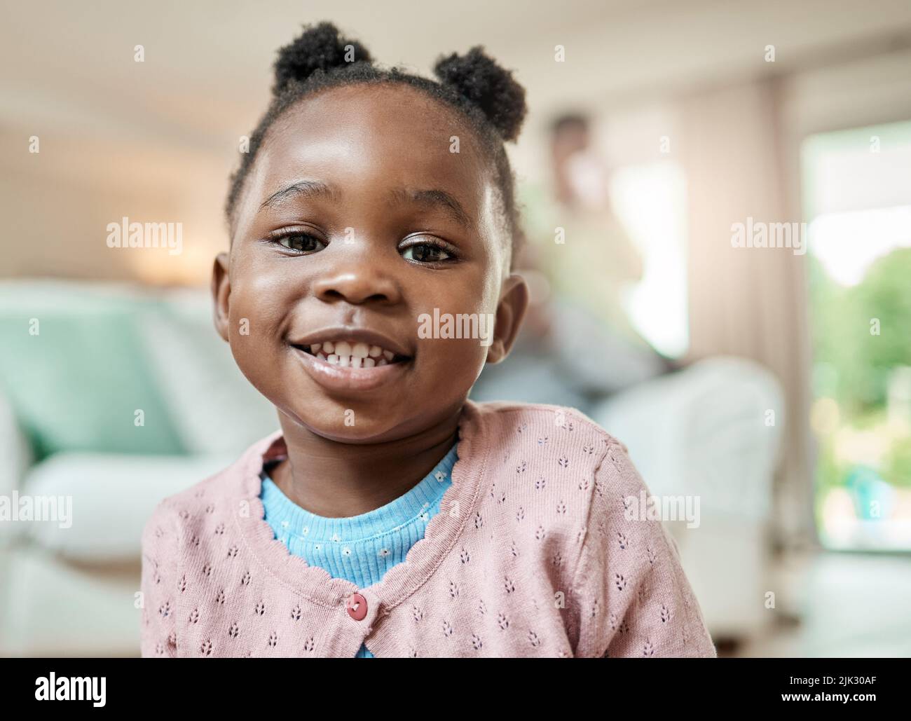 What a cutie. Cropped portrait of an adorable little girl with pigtails sitting on the living room floor at home. Stock Photo