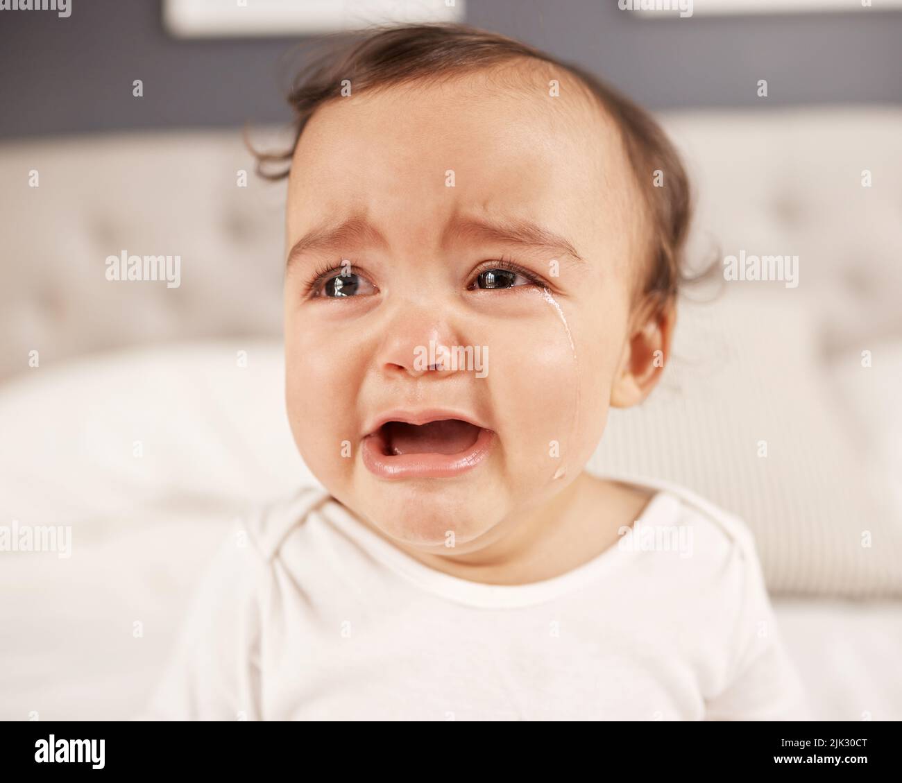 I want my mommy. an adorable little girl crying while sitting on a bed