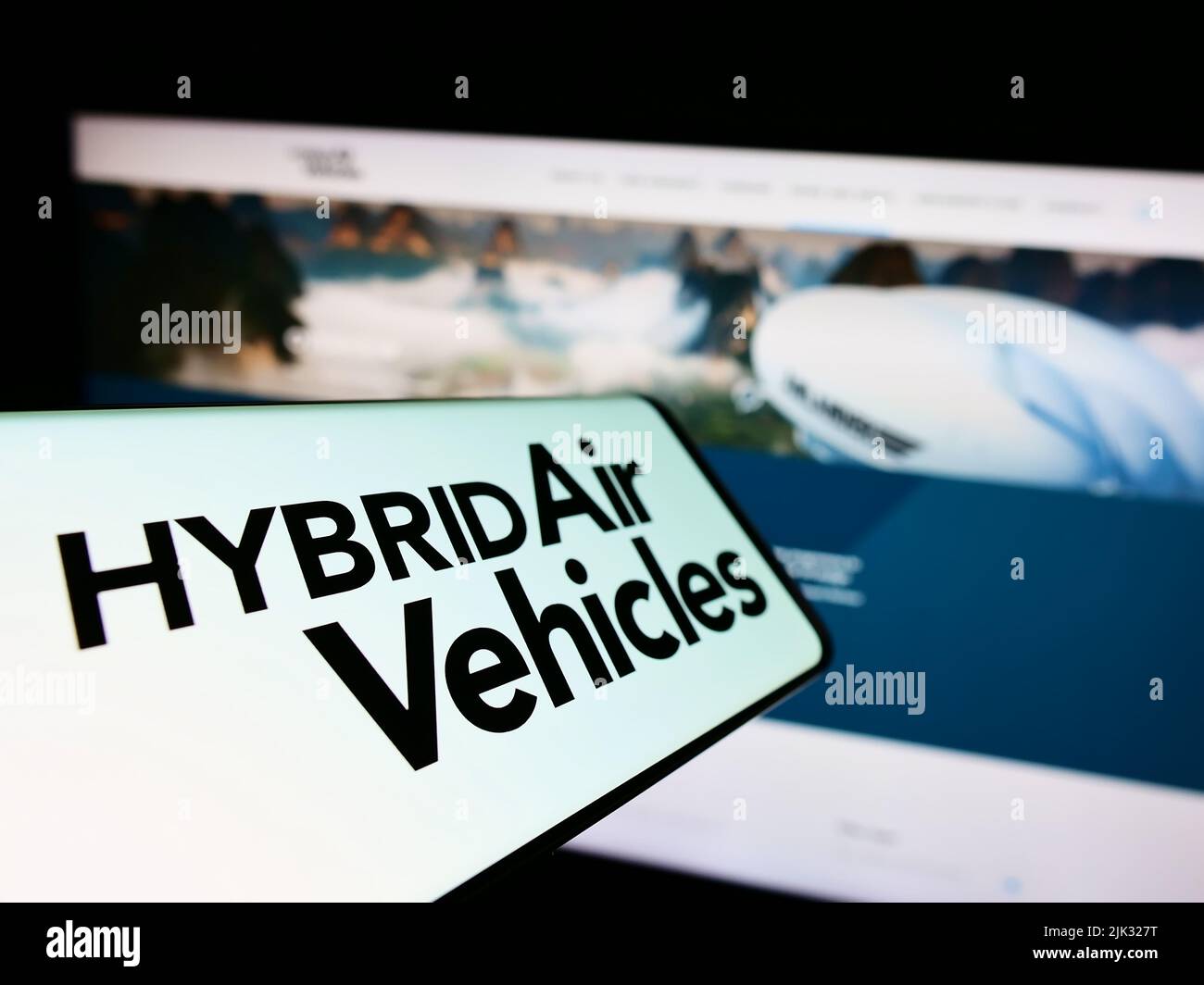 Smartphone with logo of company Hybrid Air Vehicles Limited (HAV) on screen in front of business website. Focus on center-left of phone display. Stock Photo