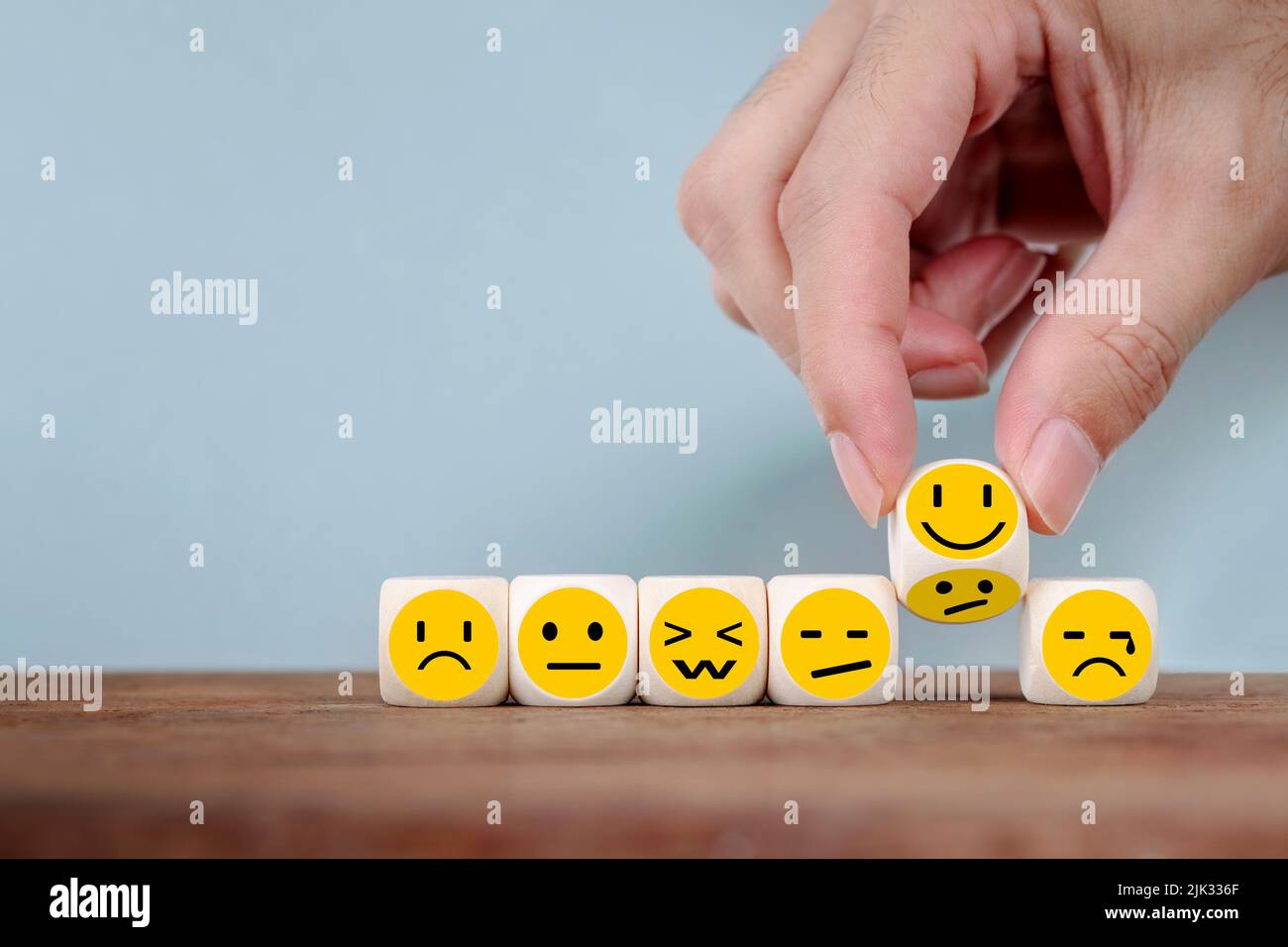 Hand Changing with smile emoticon icons  face on Wooden Cube , hand flipping unhappy turning to happy symbol Stock Photo
