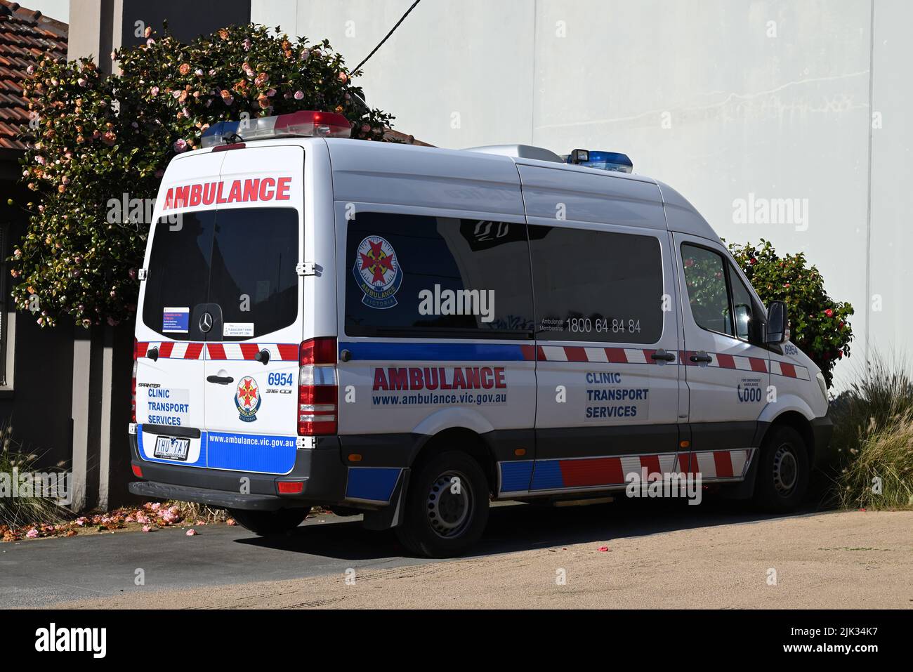 White Ambulance Victoria Clinic Transport Services vehicle, a Mercedes Benz Sprinter van, parked in a yard outside a building Stock Photo