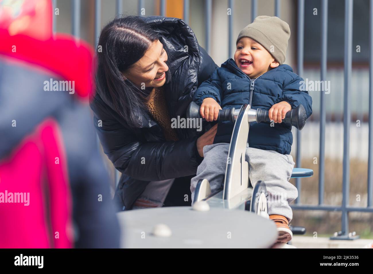 A Wonderful full of happiness dark-skinned five years of age boy on a see saw spending lovely time together with his attractive caucasian mother on a playground for kids. High quality photo Stock Photo