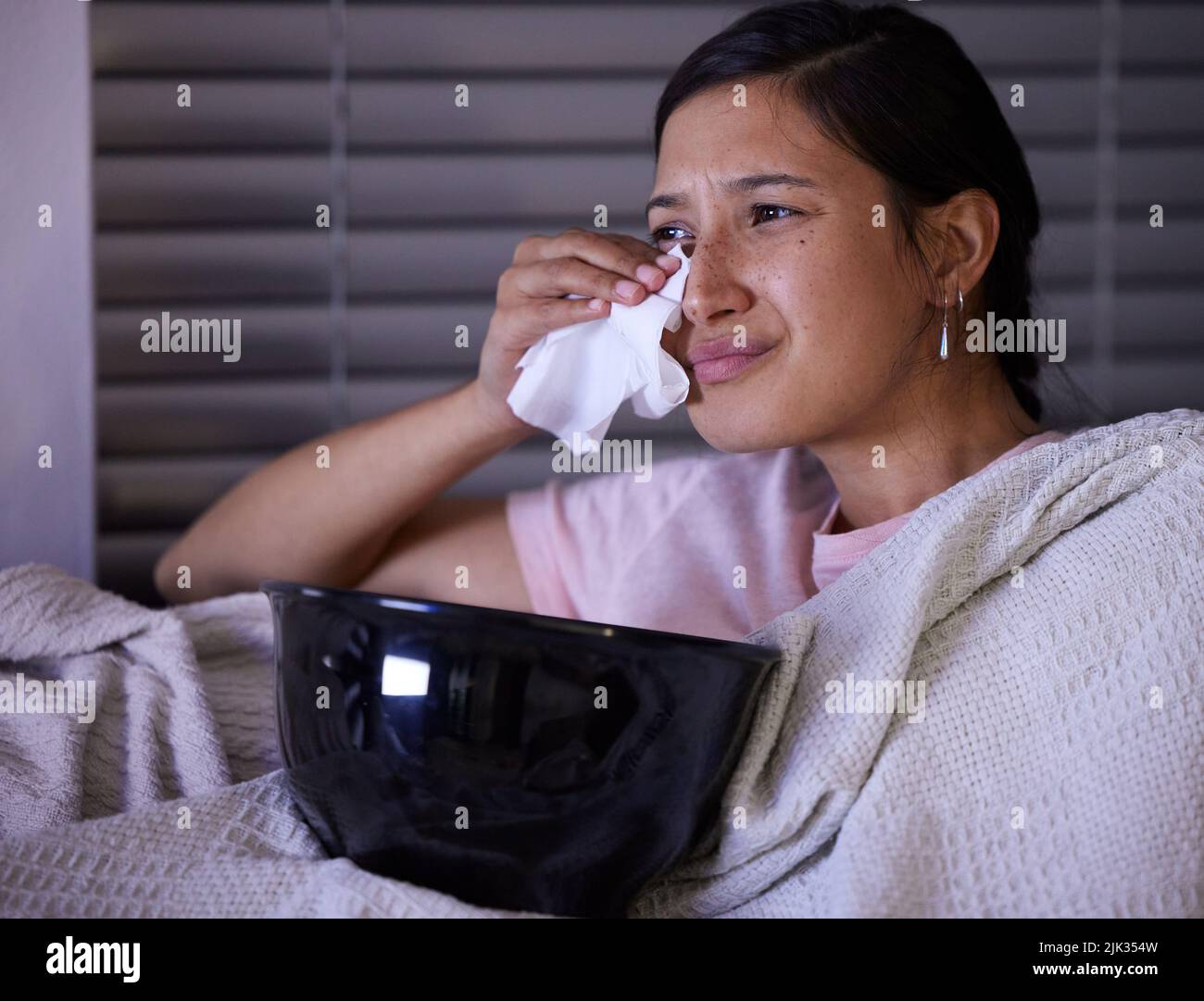 This movie is really sad. a young woman crying while watching tv at home. Stock Photo