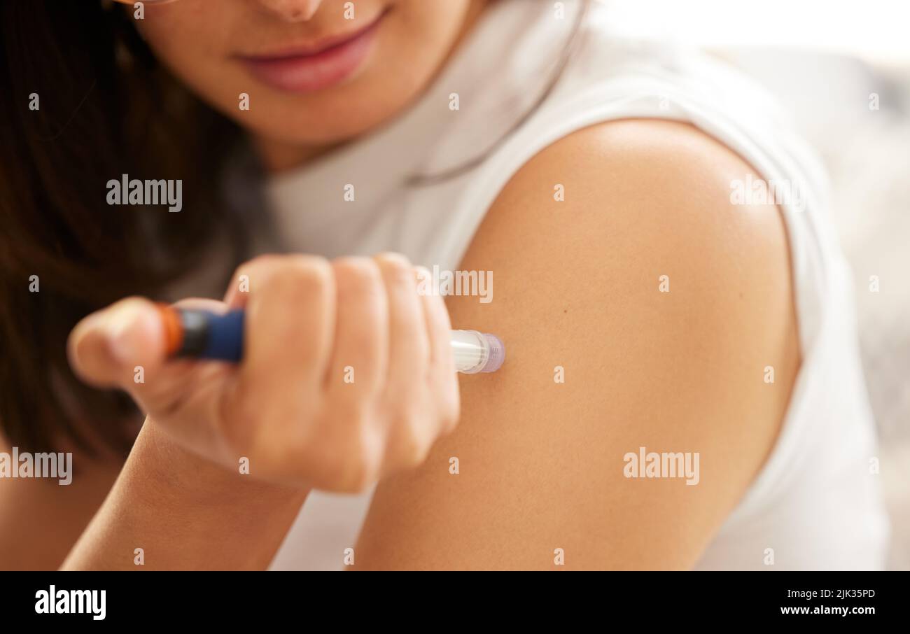 Living with diabetes. Closeup shot of an unrecognizable woman injecting herself in the arm with insulin at home. Stock Photo