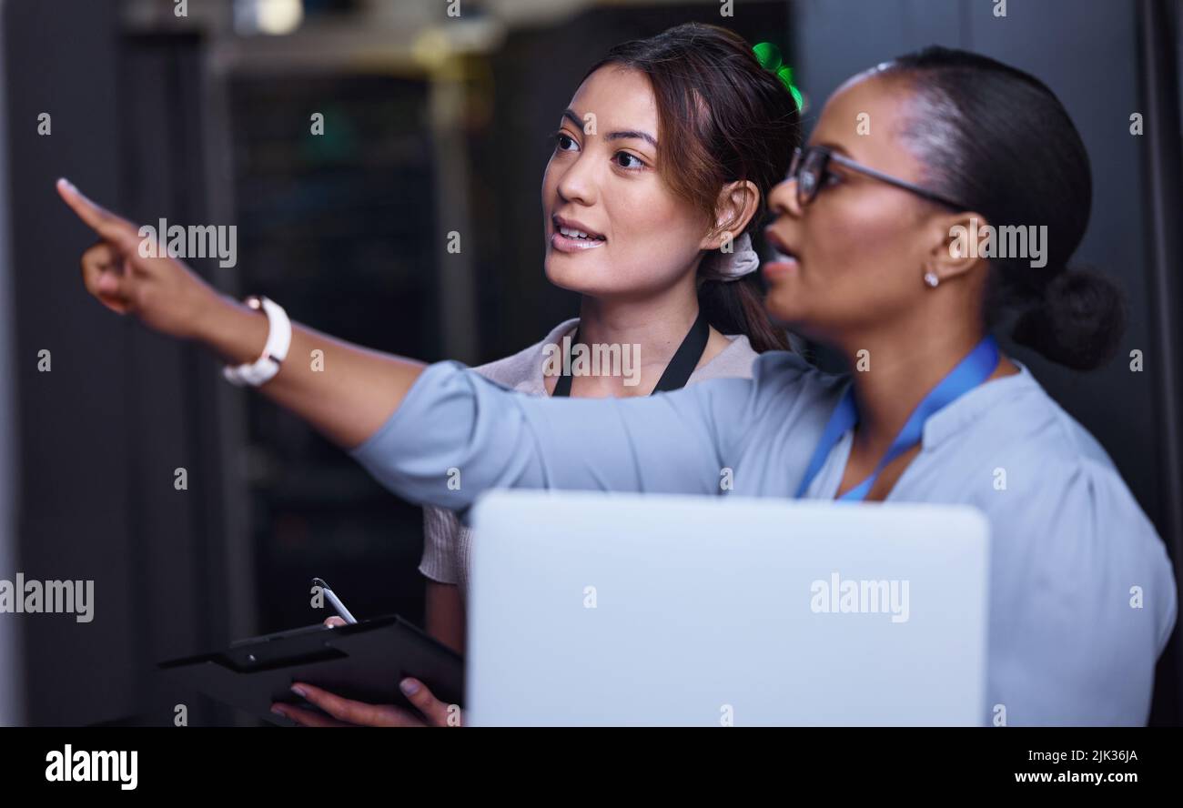 We should check that one next. two attractive young female computer programmers working together in a server room. Stock Photo