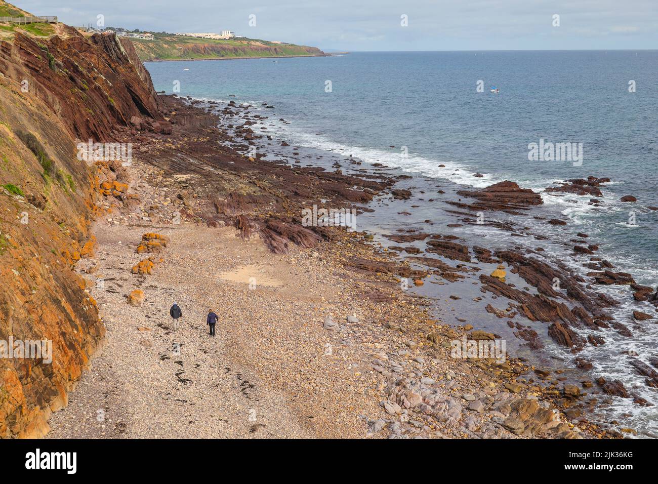 A couple walking along the rocky beach of Hallet Cove in South Australia Stock Photo