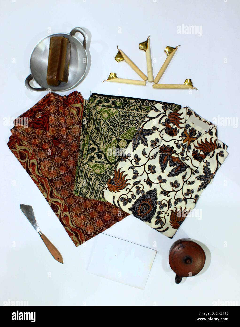 flat lay batik clotes with canting, small pan and wax earthenware glass isolated on white background Stock Photo
