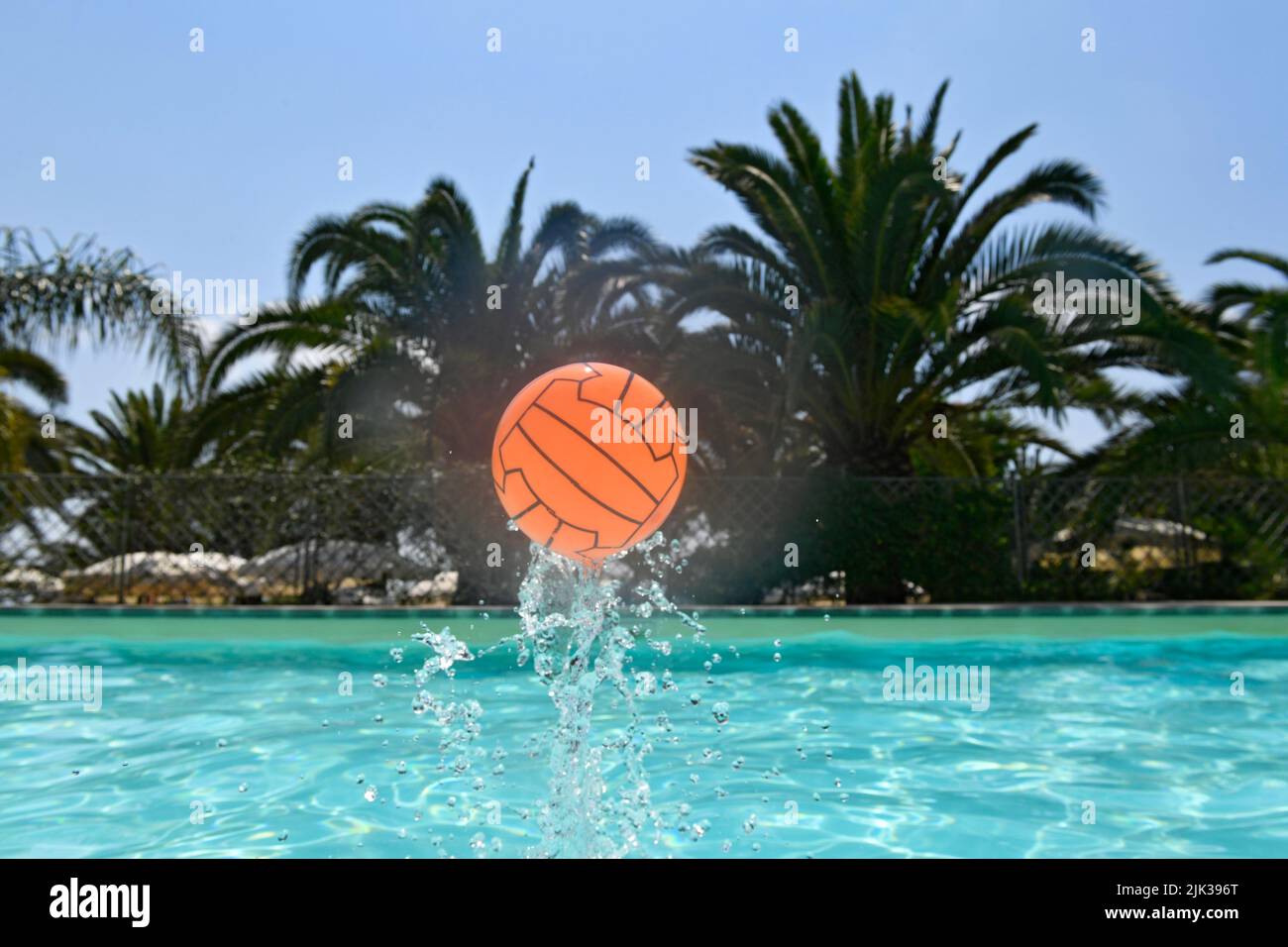 flying up orange ball from swimming pool Stock Photo