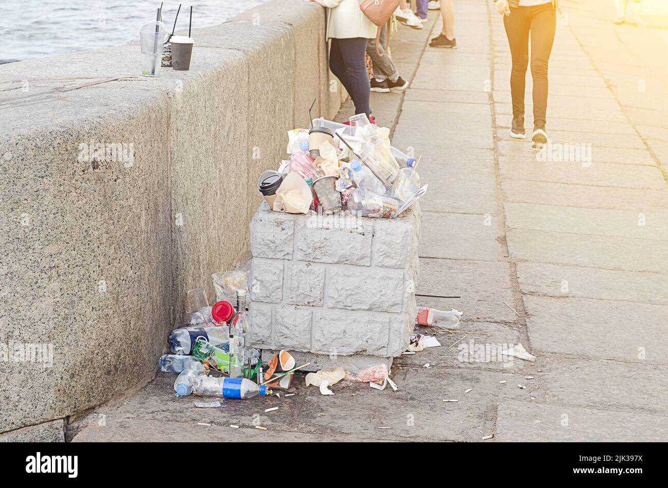 Sunset, an overflowing trash bin and scattered garbage on the embankment Stock Photo Alamy