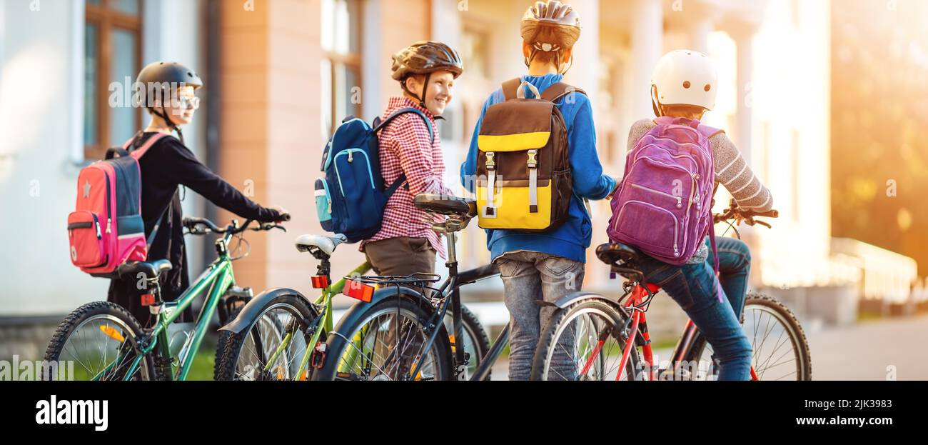 Children with rucksacks riding on bikes in the park near school Stock Photo