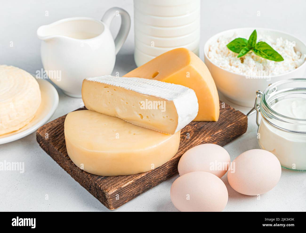 Different types of cheeses and dairy products and eggs on a light gray