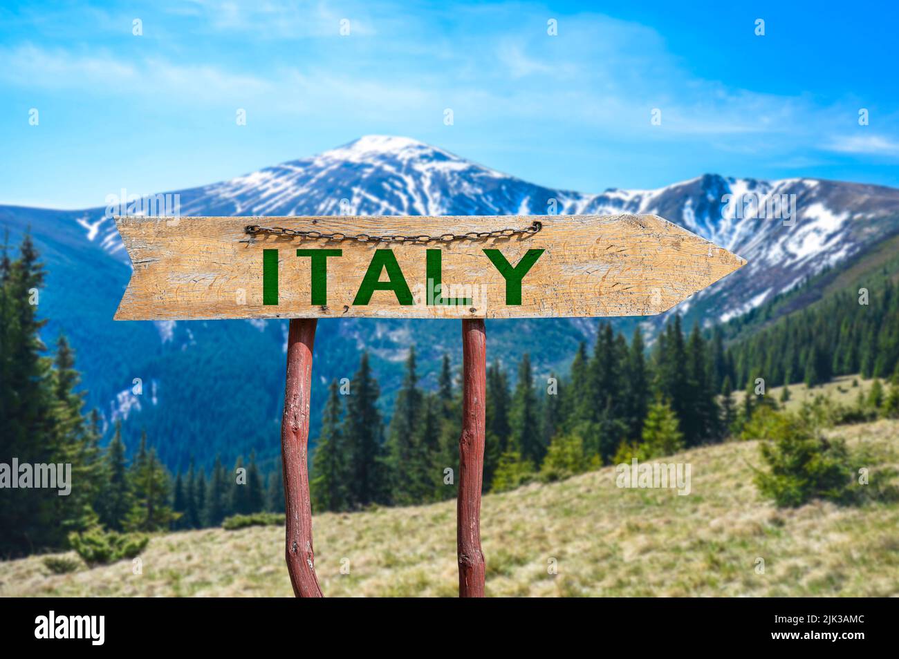 Italy wooden arrow road sign against mountains landscape. Stock Photo