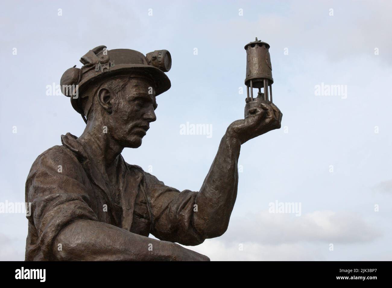 A Statue of a Coal Miner Looking at his Miner's Lamp. Stock Photo