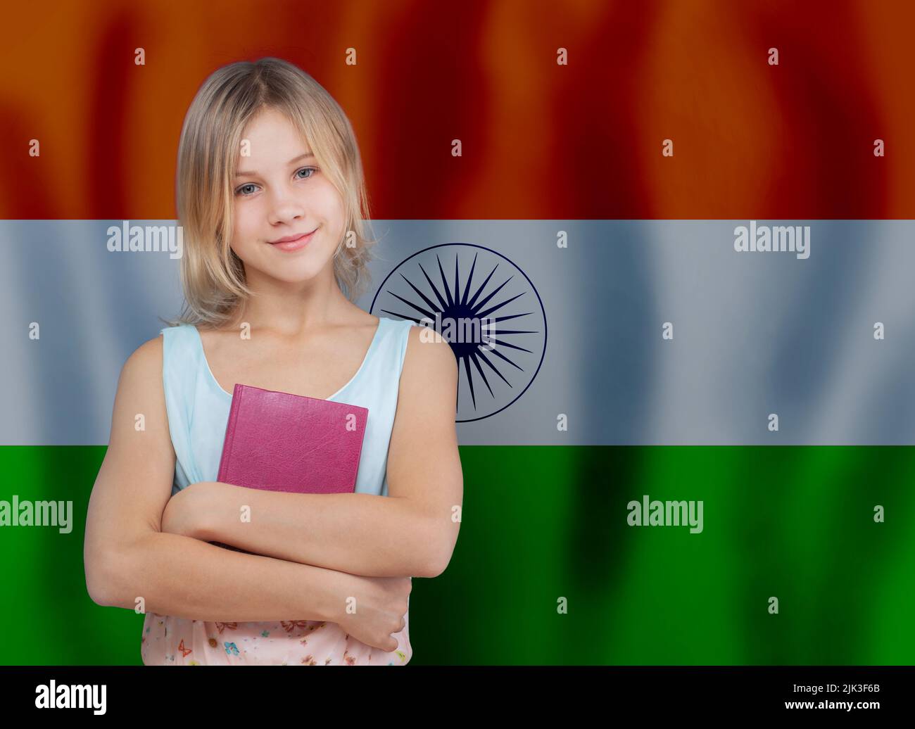 Adorable teen girl with book smiling on flag of India background. Education and school concept Stock Photo