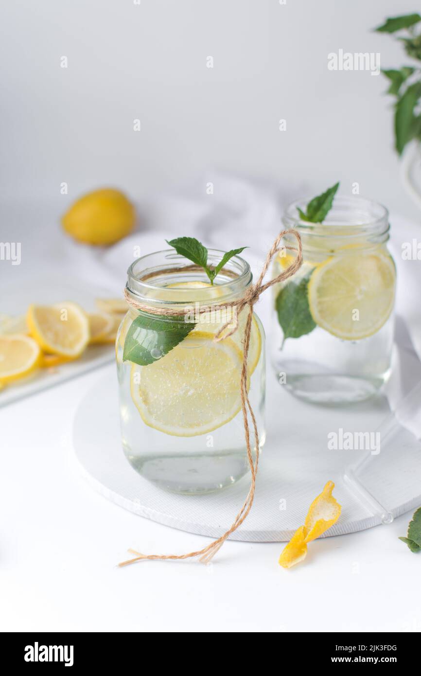 Lemon lime soda in a mason jar with a lemon slice and basil leaves, lemonade in a glass jar