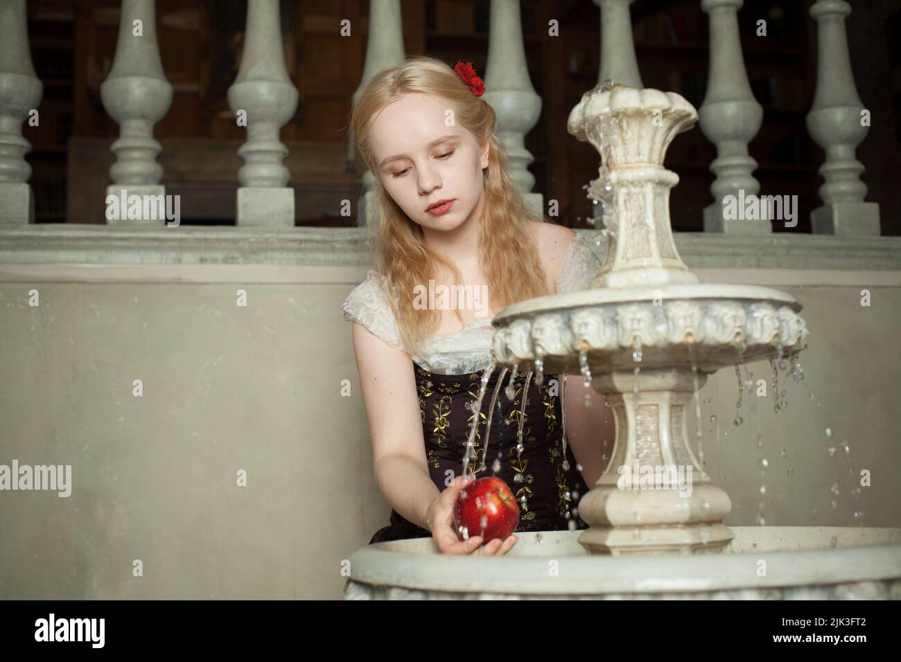 Young woman washing an apple in a vintage fountain Stock Photo