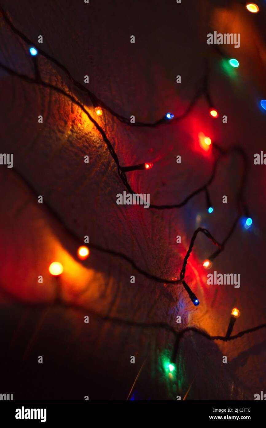 christmas garlands of lights on the wall in the house dark background