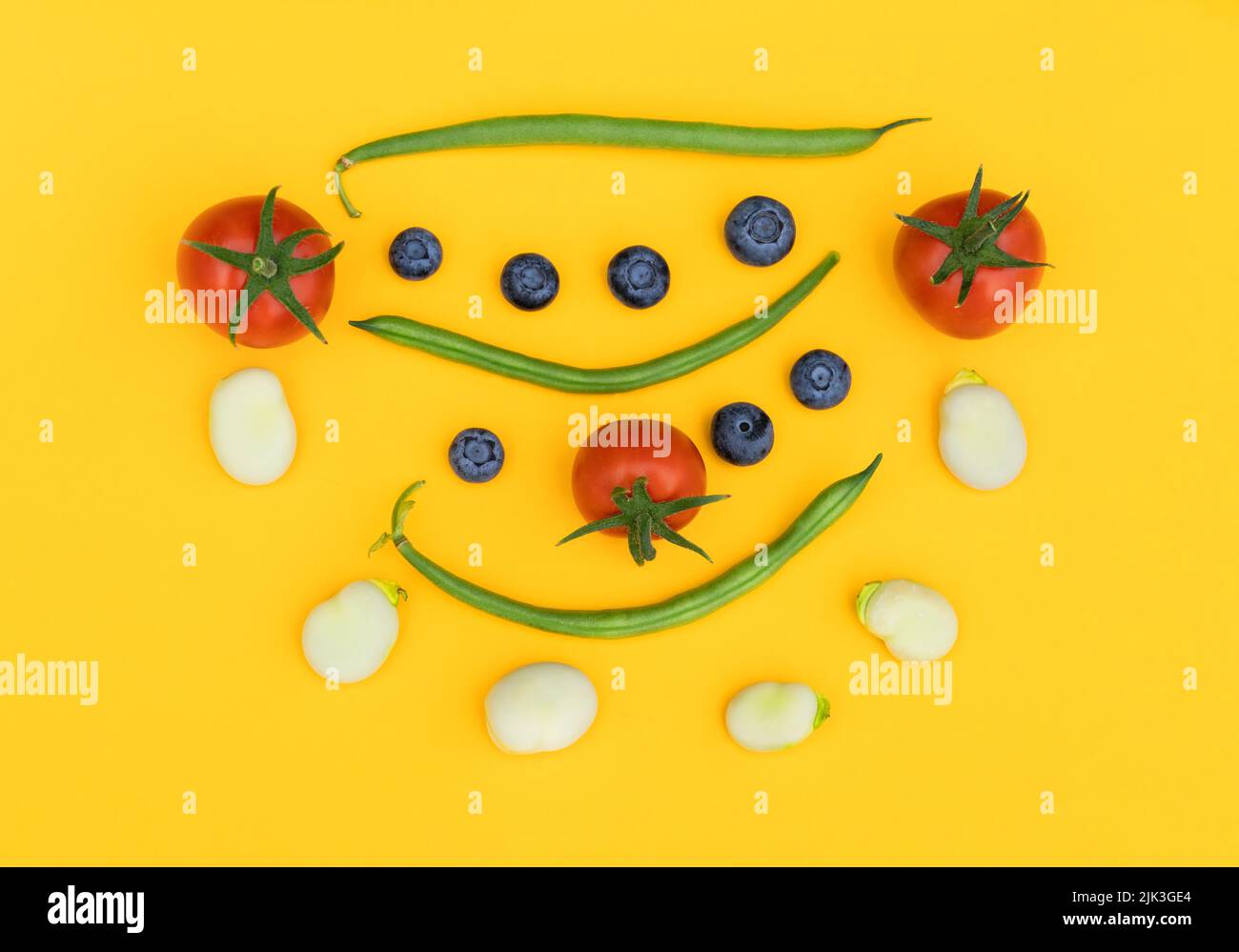The Good Life. A collection of home grown fruit and vegetables against a vibrant yellow background. Promoting a healthy lifestyle in a fun way. Stock Photo
