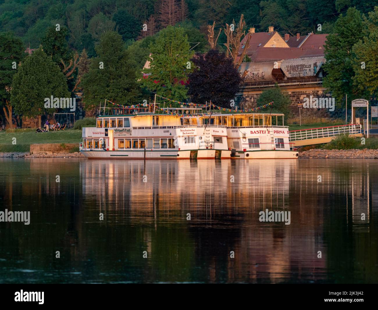 Boats on the Elbe river are waiting. The boat ride on the water is a famous tourist attraction. The sunset light is shining on the ships and the water Stock Photo
