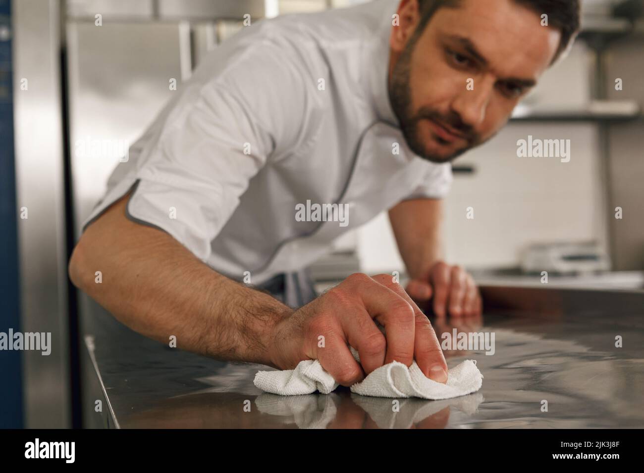 Close up of handsome male chef cleaning his workplace on kitchen in