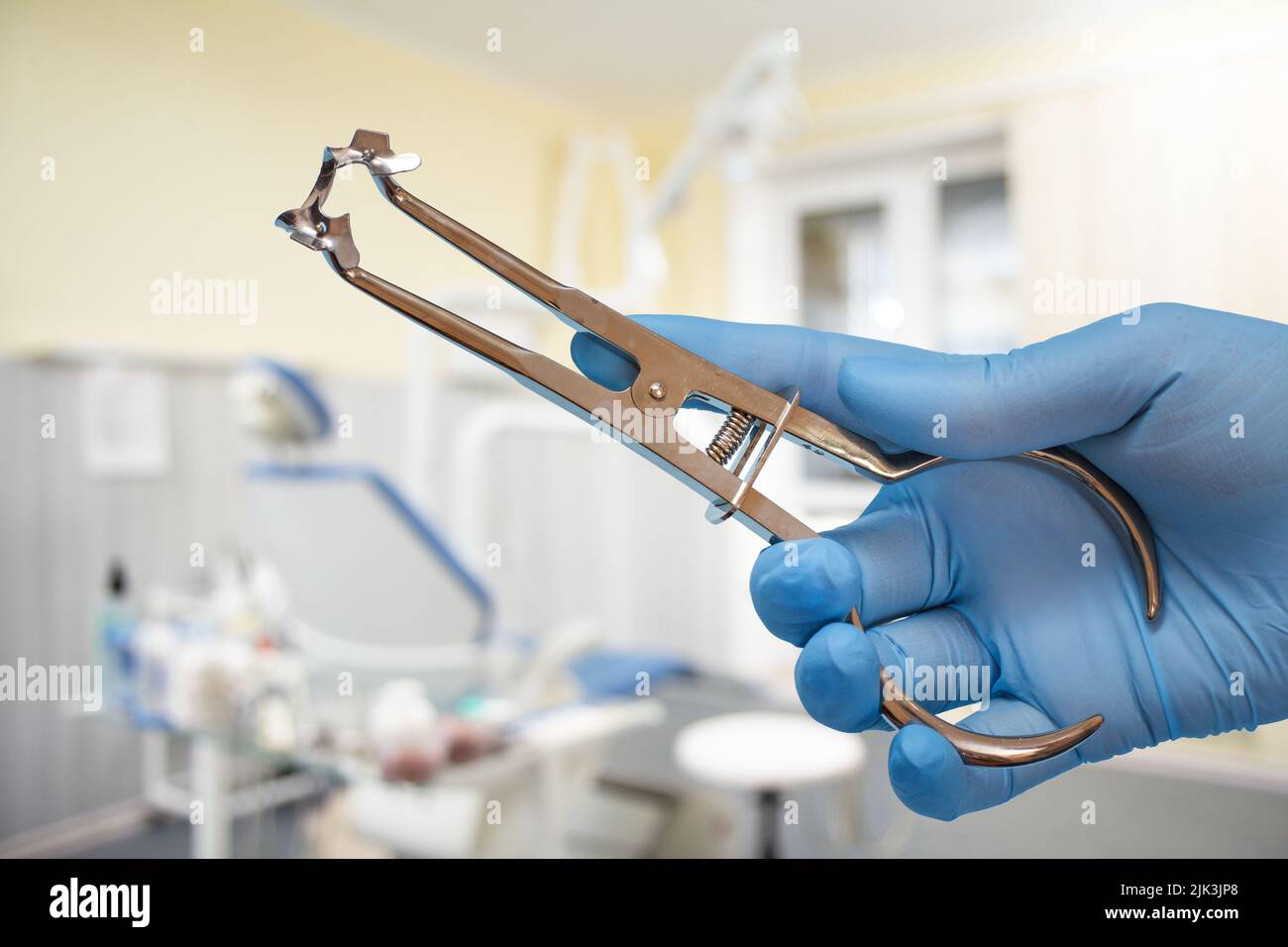 Dentist's hand in glove with rubber dam clamp forceps and clamp Stock