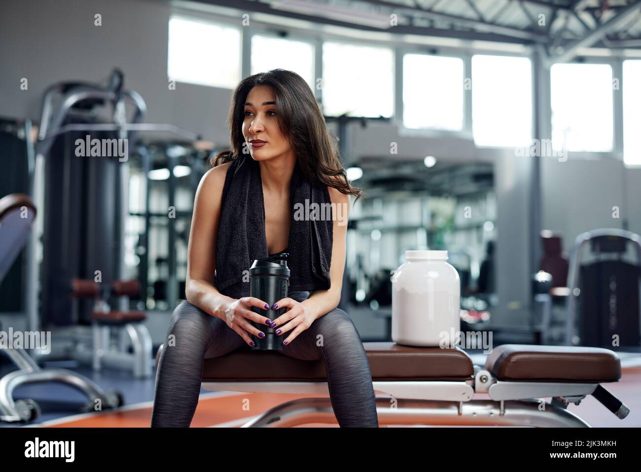Young active woman taking a break in the gym and drinking protein shake. Stock Photo