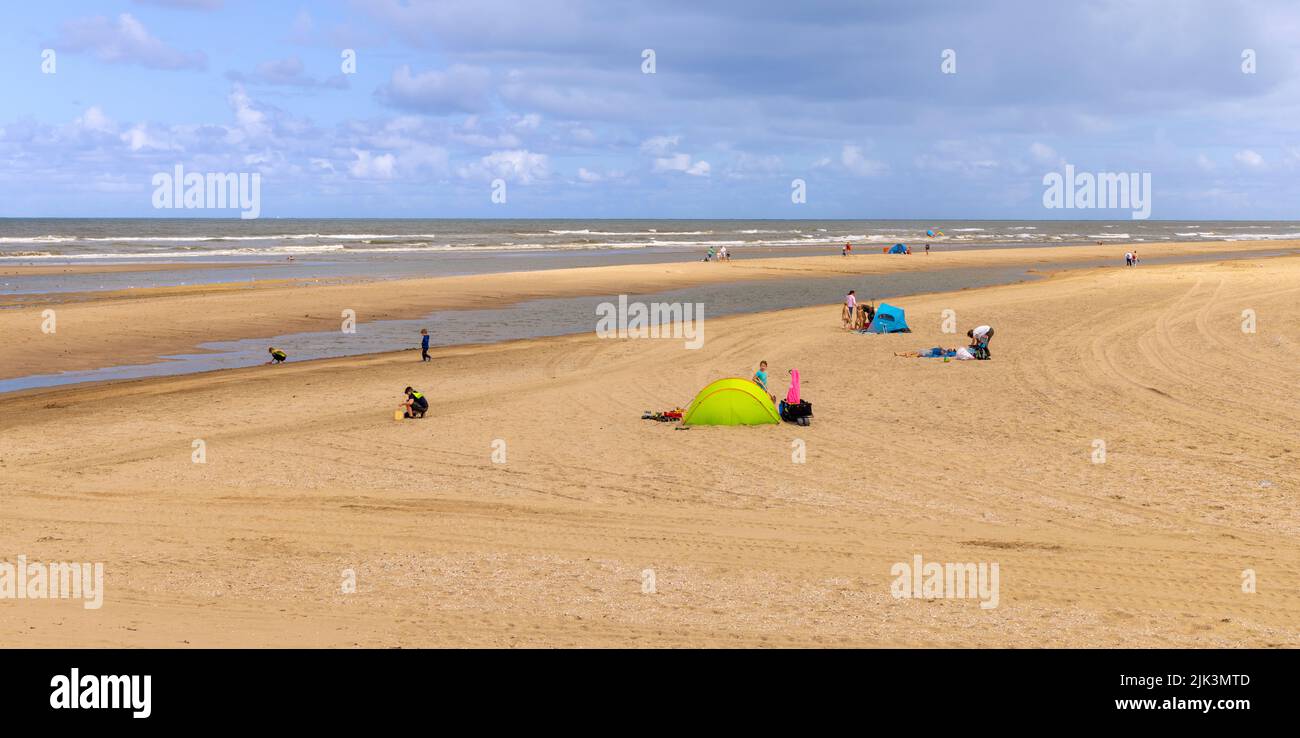 Summertime along the North Sea: People relaxing and sunbathing on the beach in Katwijk, South Holland, The Netherlands. Stock Photo