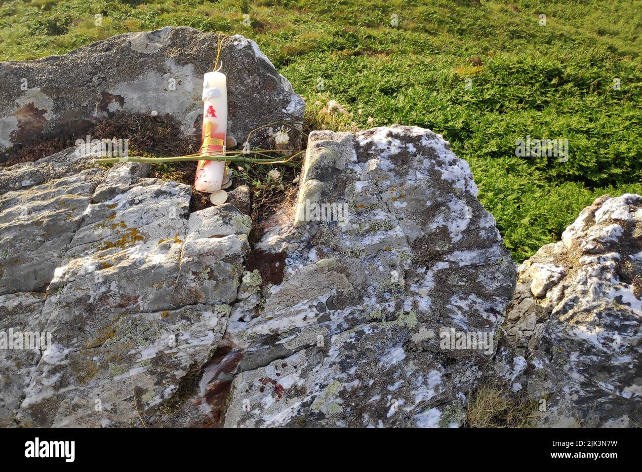 Candle, a flower and a few coins as an offering near the sacrifice of a black goat at Roc'h Bichourel in the Monts d'Arrée on the day of the fire. Stock Photo