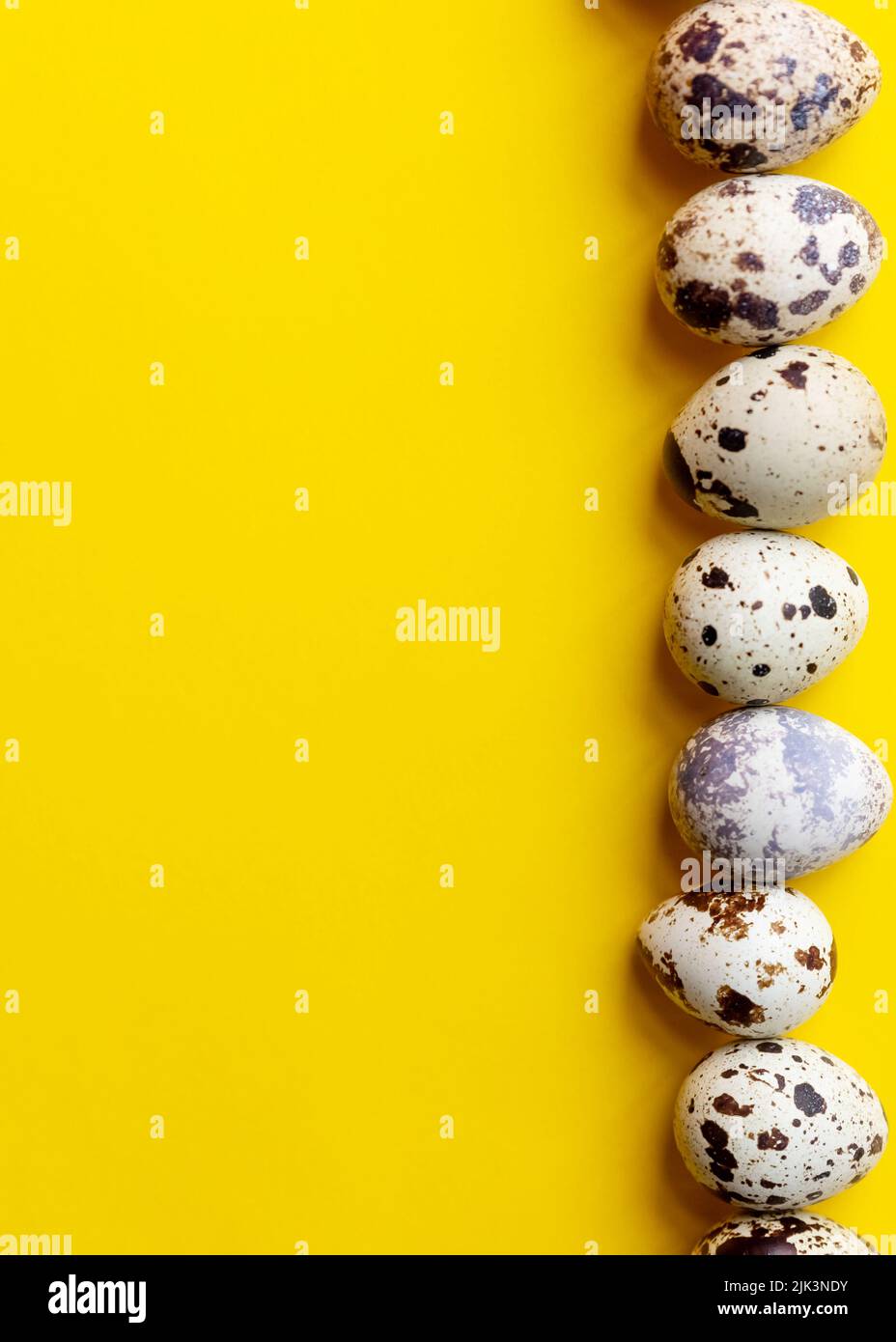 Top view - Quail eggs on bright yellow background. Minimal Happy Easter composition. Stock Photo
