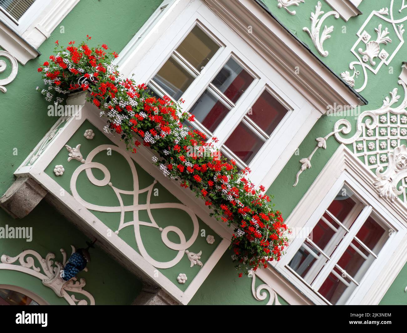 SCHARDING, AUSTRIA - JULY 12, 2019:  Pretty geranium flowers on balcony of Baroque style town house in the Old Town Stock Photo