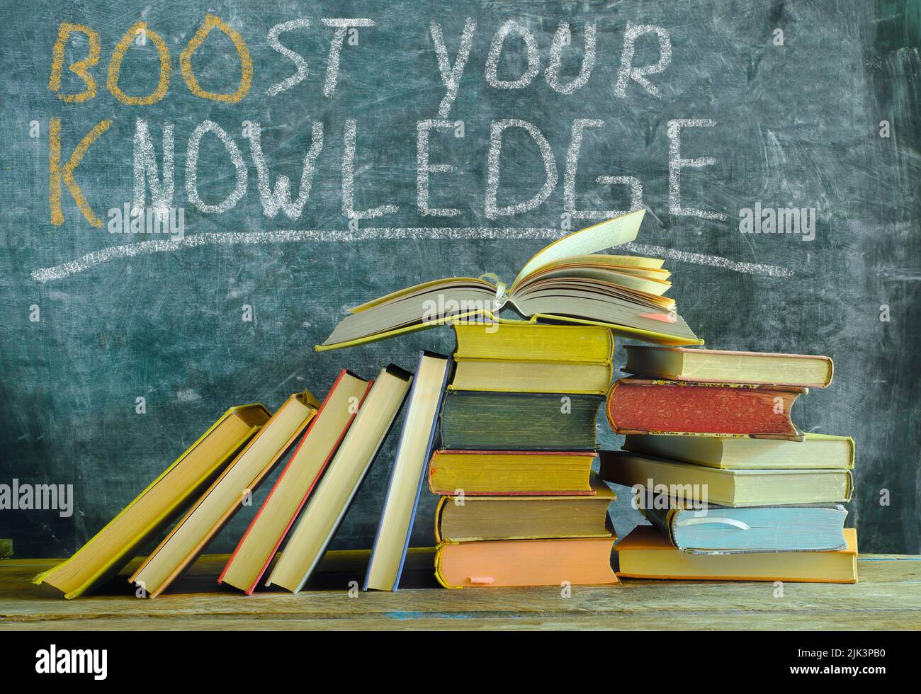 open book in front of a black board with slogan boost your knowledge,learning,education,home office and back to school concept Stock Photo