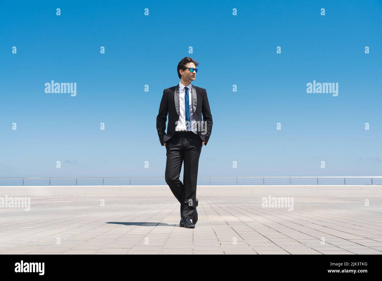 Happy and handsome adult businessman wearing elegant suit standing outdoors, full body portrait Stock Photo