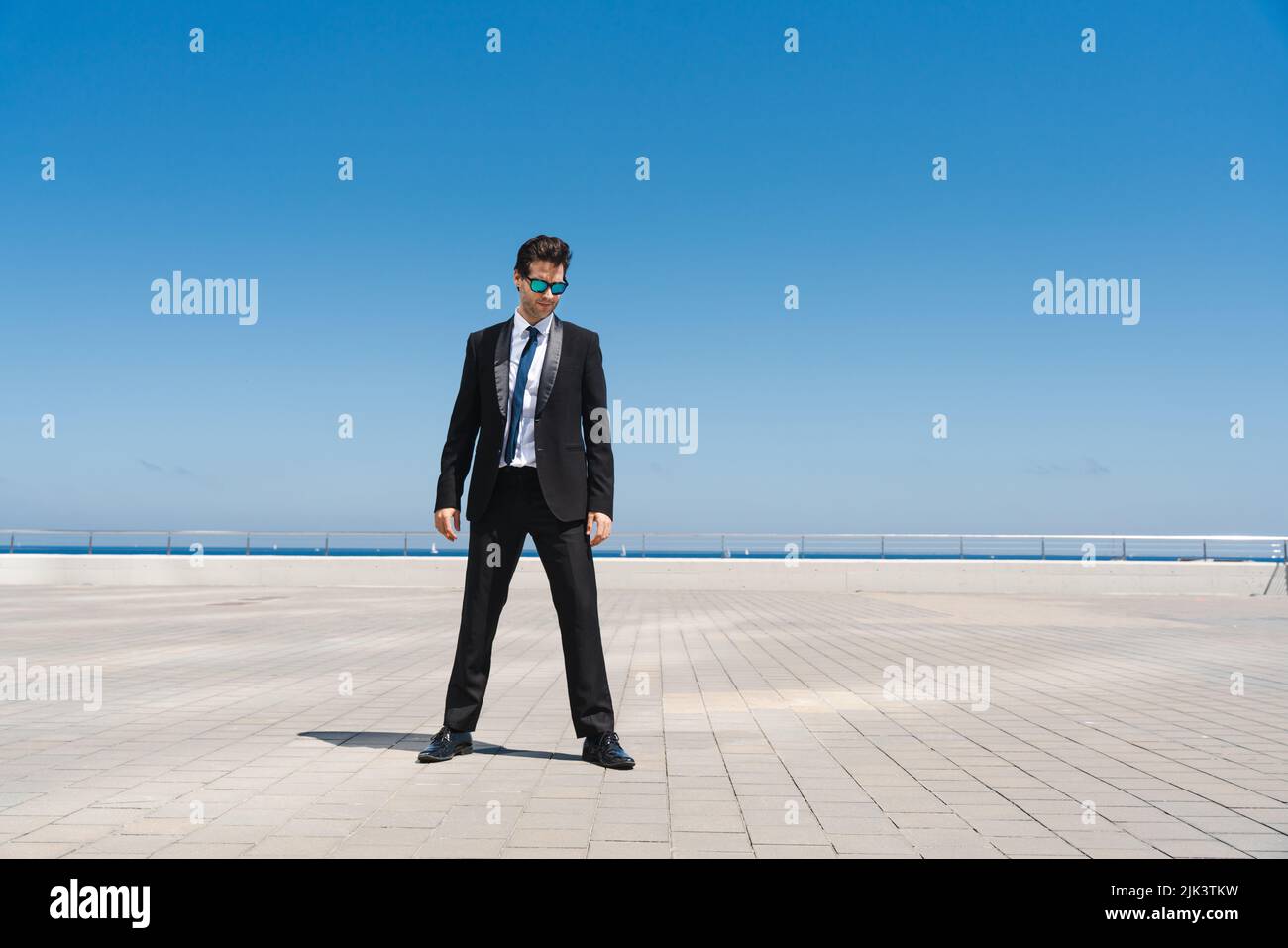 Happy and handsome adult businessman wearing elegant suit standing outdoors, full body portrait Stock Photo