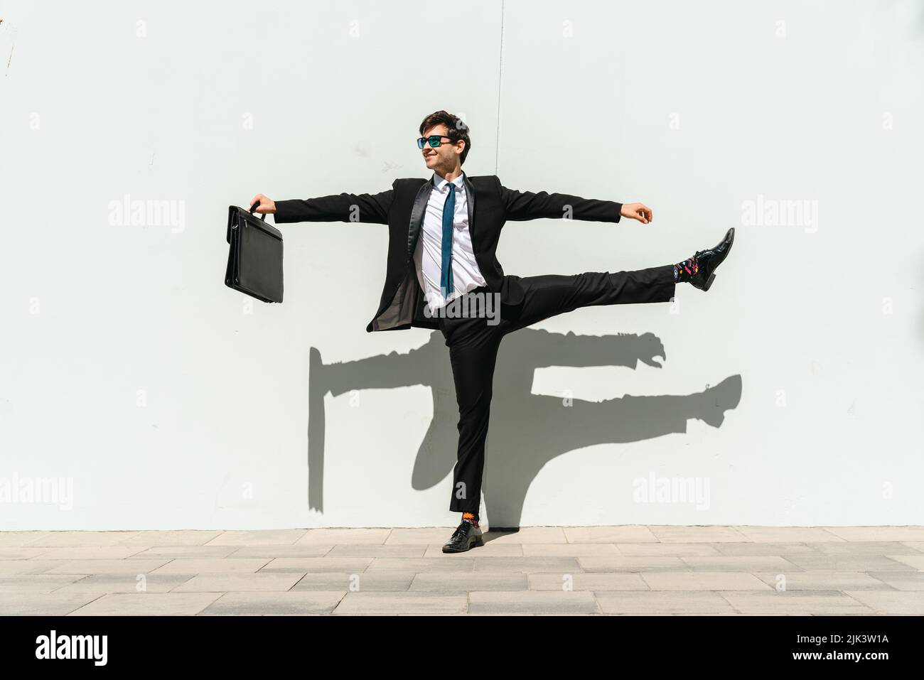 Happy and handsome adult businessman wearing elegant suit doing acrobatic trick moves in the city, alternative concept for business advertisement with Stock Photo