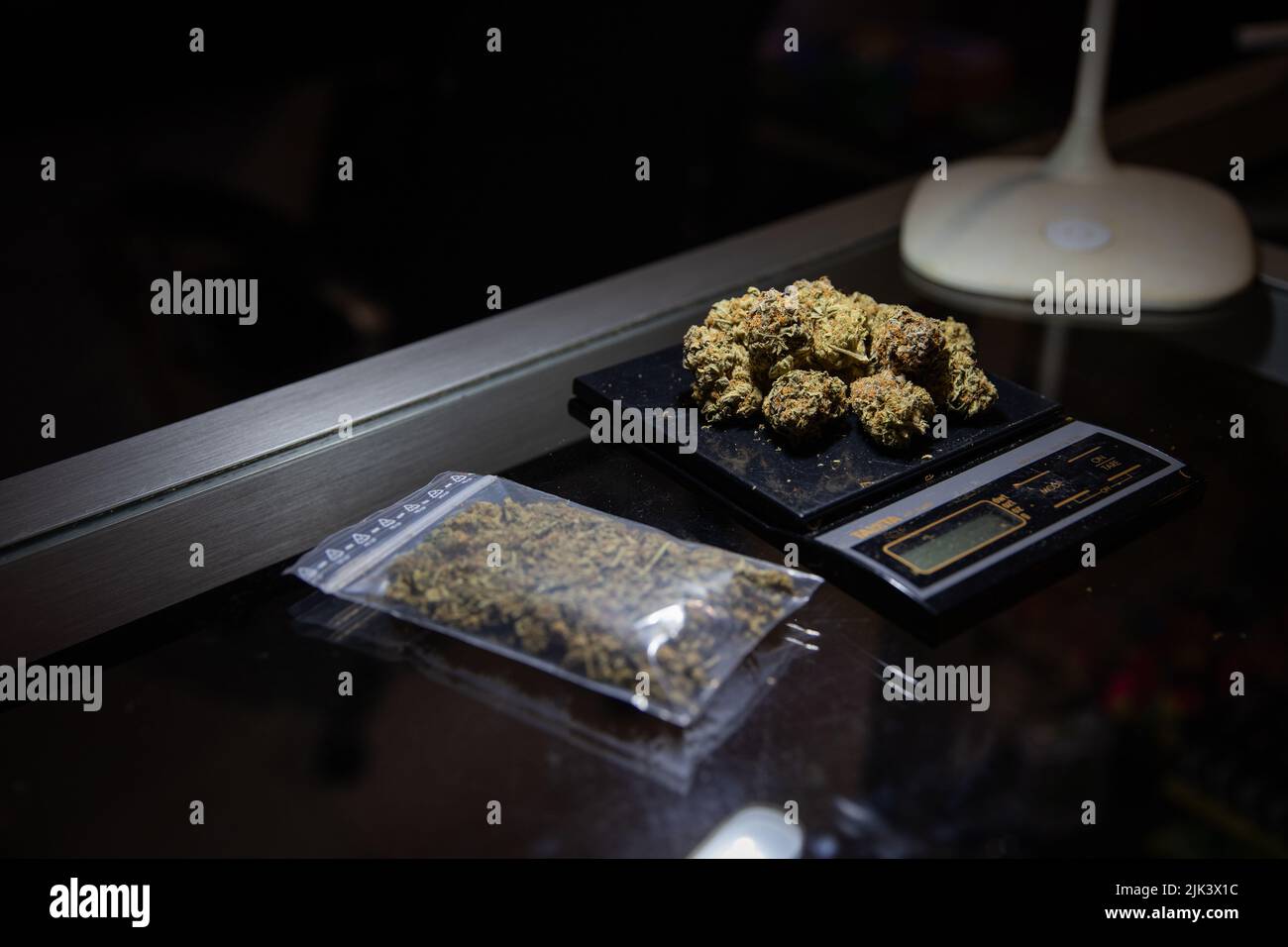 https://c8.alamy.com/comp/2JK3X1C/rraw-marijuana-weighed-on-a-scale-next-to-a-bag-of-marijuana-ready-to-be-sold-2JK3X1C.jpg