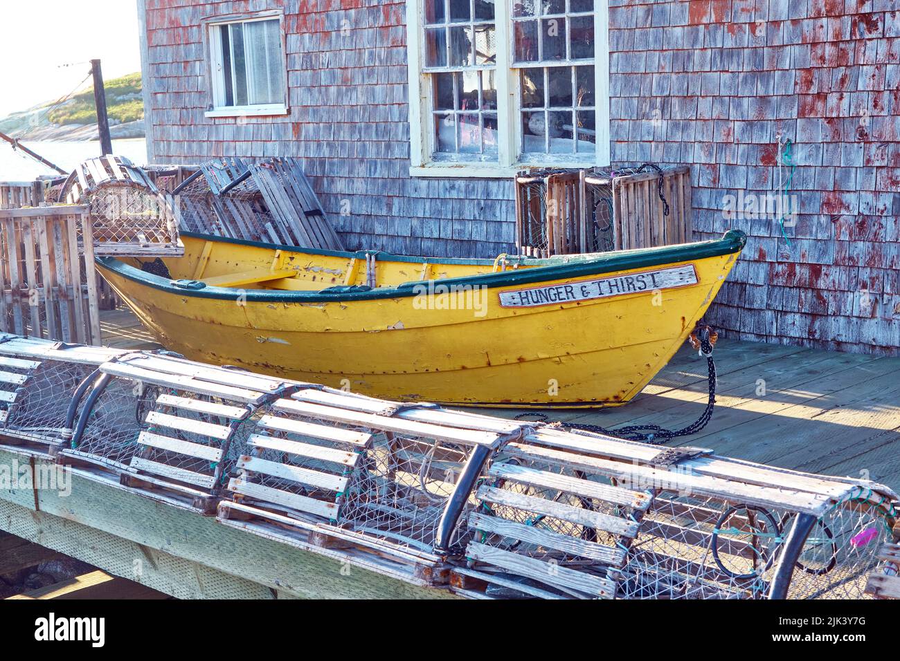 Small yellow fishing dorey sitting on the dock outside a weather fish hut in the small coasta fishing village of Peggy's Cove Nova Scotia. Stock Photo